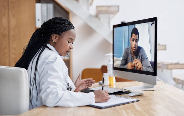 A imagem mostra uma profissional de saúde de frente para uma tela do computador em que conversa com um paciente, ilustrando a telessaúde