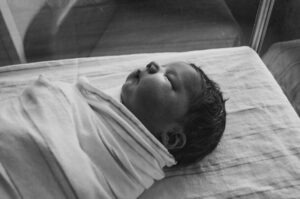 Recém-nascido A imagem em preto e branco mostra um bebê enrolado em uma manta branca